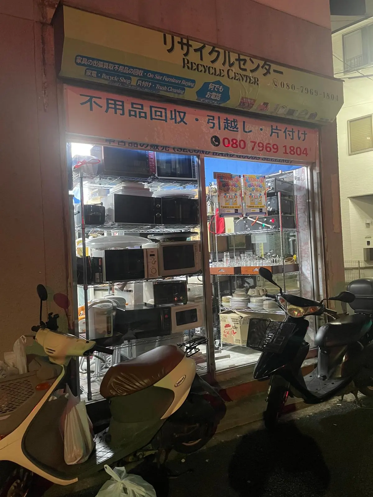 夜の店舗正面。看板に店名と不用品回収の文字がある